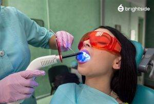 Woman receiving teeth whitening treatment at dentist with Brightside logo