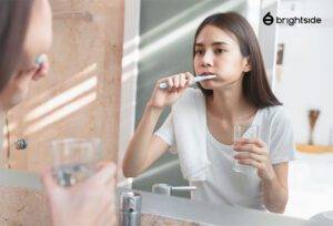 Woman brushing teeth in front of the mirror