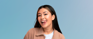 Asian woman smiling cheekily with tongue out with blue background
